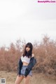 A woman standing in the middle of a dirt field.