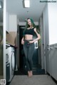 A woman standing in a laundry room next to a washing machine.