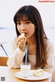 A woman sitting at a table eating a piece of food.