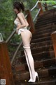 A woman in a white lingerie is standing on some stairs.