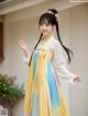 A young girl wearing a yellow and blue hanfu dress.