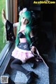 A woman with green hair sitting on a window sill.