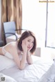 A woman laying on top of a bed in a white lingerie.