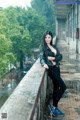 A woman in a black leather jacket leaning against a wall.