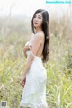 A woman in a white dress standing in tall grass.